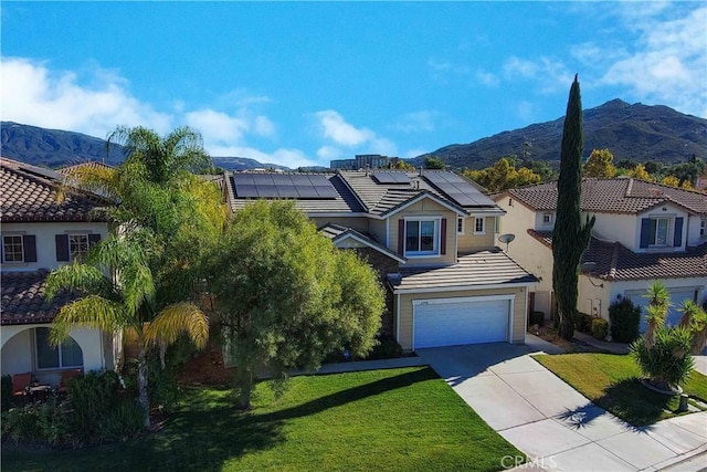 view of front facade featuring a mountain view, solar panels, a garage, and a front yard