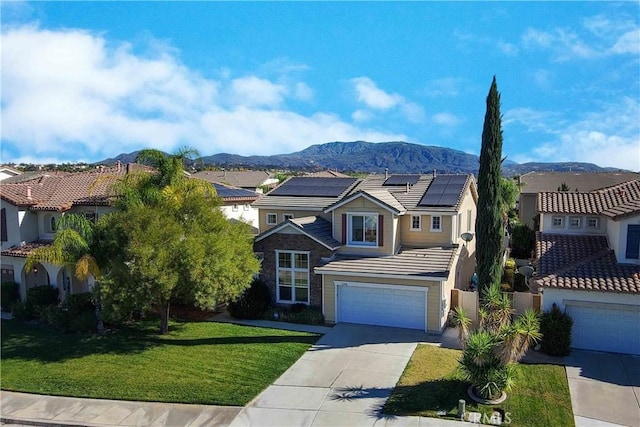 view of front of home featuring a mountain view, solar panels, a garage, and a front lawn