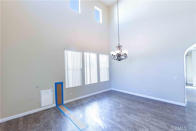 empty room with a chandelier, a high ceiling, and dark hardwood / wood-style flooring