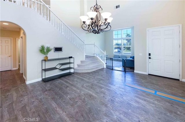 entryway featuring a chandelier, a towering ceiling, and dark wood-type flooring