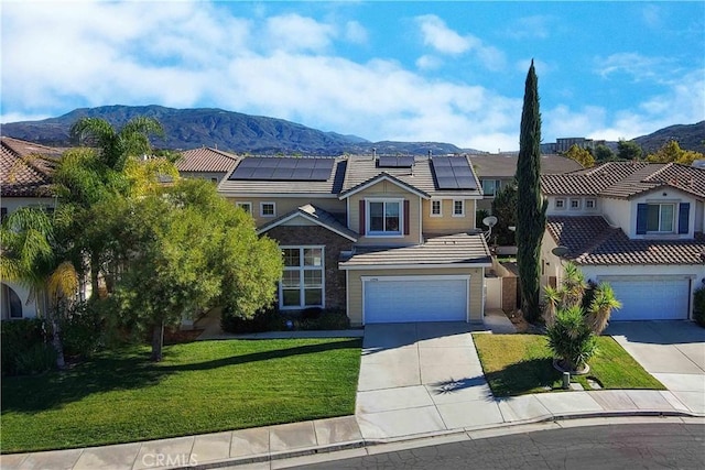 view of front of house with solar panels, a mountain view, a front yard, and a garage