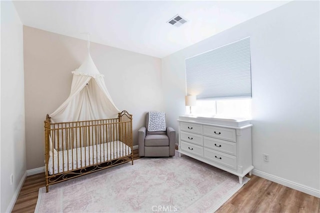 bedroom featuring light hardwood / wood-style flooring and a nursery area