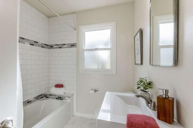 bathroom featuring sink, a healthy amount of sunlight, and tiled shower / bath