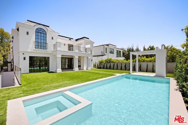 back of property featuring a yard, a balcony, a patio, and a pool with hot tub