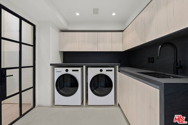 clothes washing area with cabinets, washer and clothes dryer, and sink