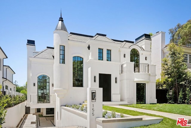 view of front of property featuring a balcony and a front lawn