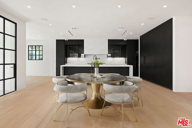 kitchen featuring tasteful backsplash, a kitchen island with sink, sink, and light hardwood / wood-style floors