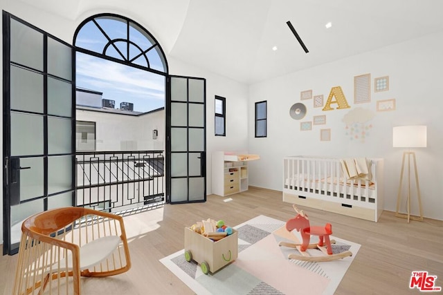 bedroom featuring light hardwood / wood-style floors and high vaulted ceiling