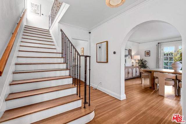 stairs featuring wood-type flooring and ornamental molding