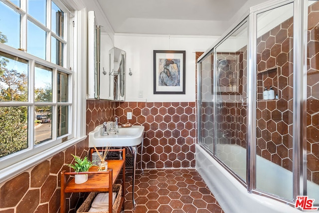 bathroom with tile patterned floors, sink, shower / bath combination with glass door, and tile walls