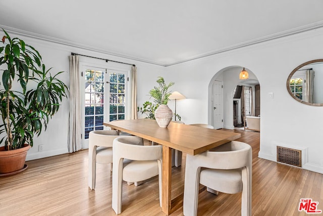 dining room with light hardwood / wood-style floors and crown molding