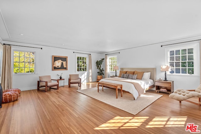 bedroom with multiple windows, ornamental molding, and light wood-type flooring