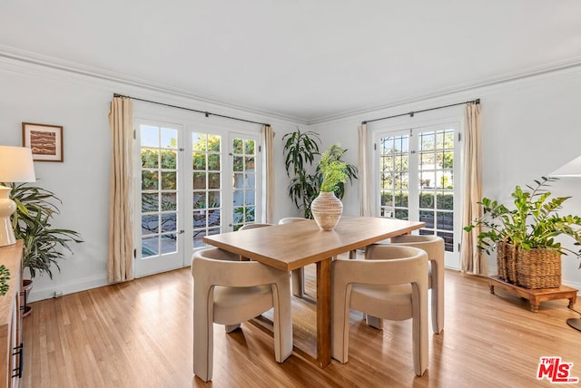 dining space with crown molding, french doors, and light hardwood / wood-style floors