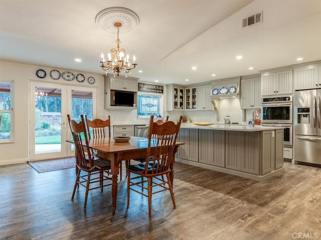 dining area featuring french doors, hardwood / wood-style floors, a chandelier, and vaulted ceiling