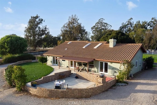 back of house with french doors, a patio, and a lawn