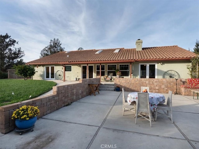 back of property featuring a lawn, a patio, and french doors