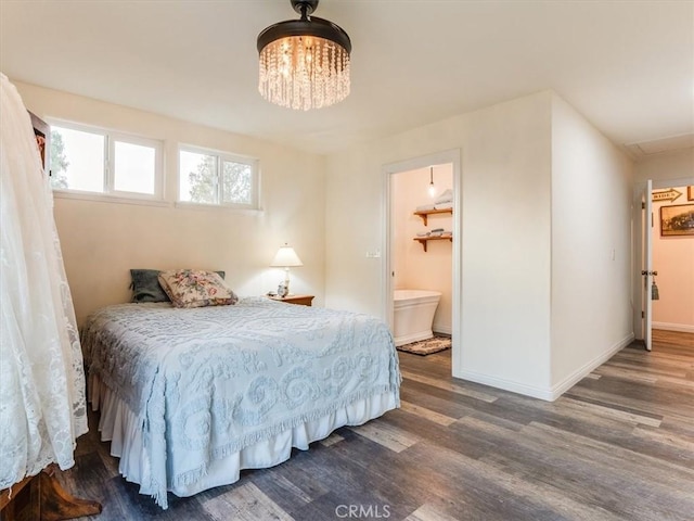 bedroom with a chandelier, a walk in closet, dark hardwood / wood-style floors, and ensuite bath