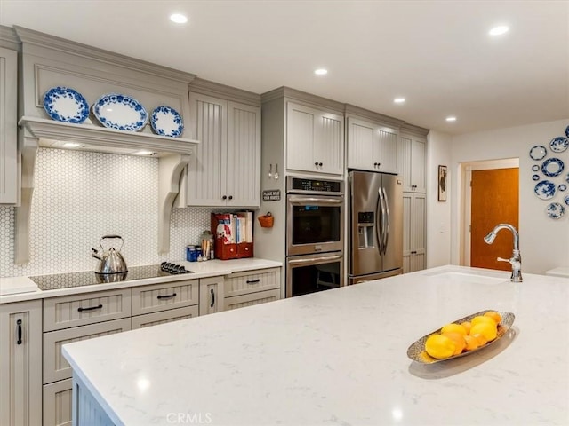 kitchen featuring gray cabinetry, sink, decorative backsplash, appliances with stainless steel finishes, and light stone counters