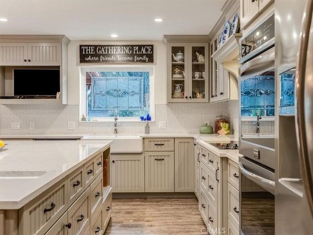 kitchen featuring sink, decorative backsplash, light wood-type flooring, cream cabinetry, and stainless steel appliances