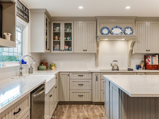 kitchen featuring light wood-type flooring, cream cabinets, backsplash, and stainless steel dishwasher