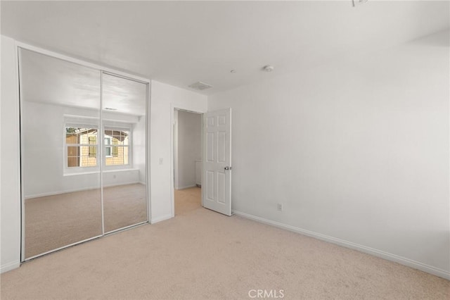 unfurnished bedroom with light carpet and a closet