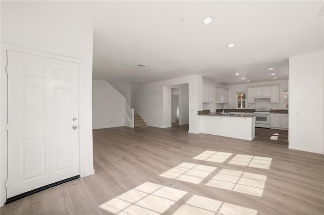 kitchen featuring kitchen peninsula, a kitchen breakfast bar, light wood-type flooring, white range oven, and white cabinetry