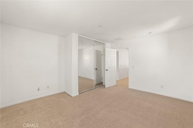 unfurnished bedroom with light carpet and a closet