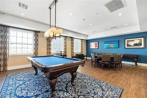 rec room with hardwood / wood-style floors, an inviting chandelier, a raised ceiling, and pool table