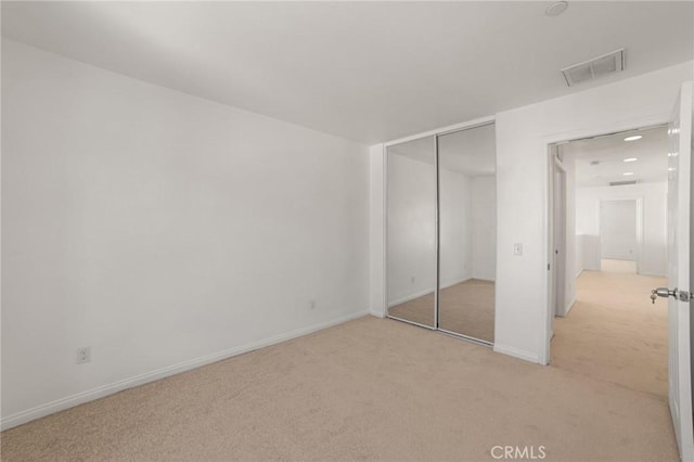 unfurnished bedroom with light carpet and a closet