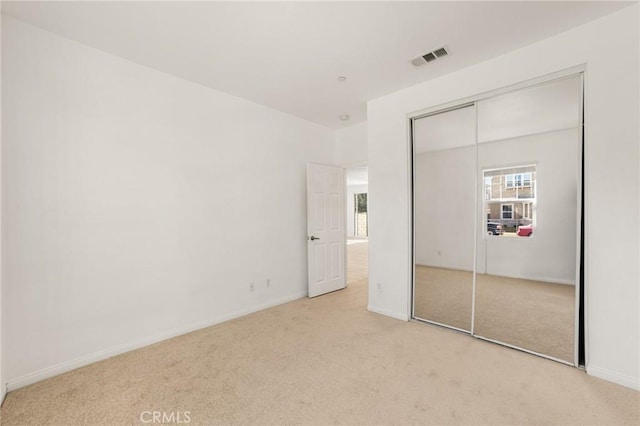 unfurnished bedroom featuring light carpet and a closet