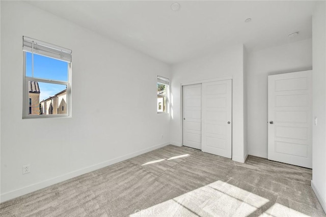 unfurnished bedroom with a closet, light carpet, and multiple windows