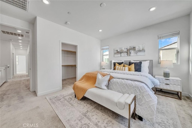 bedroom featuring light carpet, a closet, a spacious closet, and multiple windows