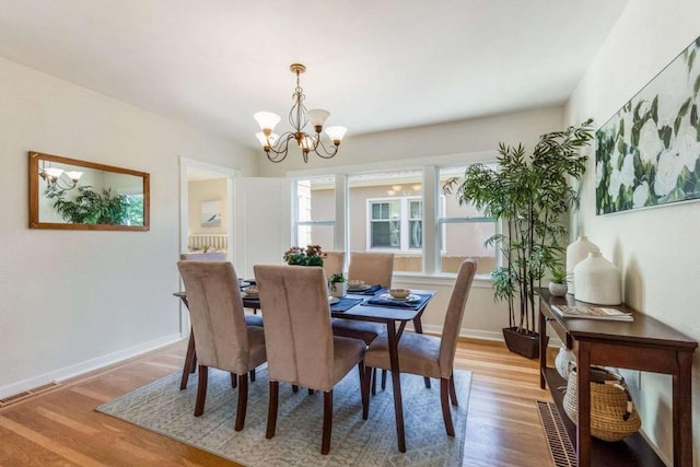 dining space with a notable chandelier and light hardwood / wood-style flooring