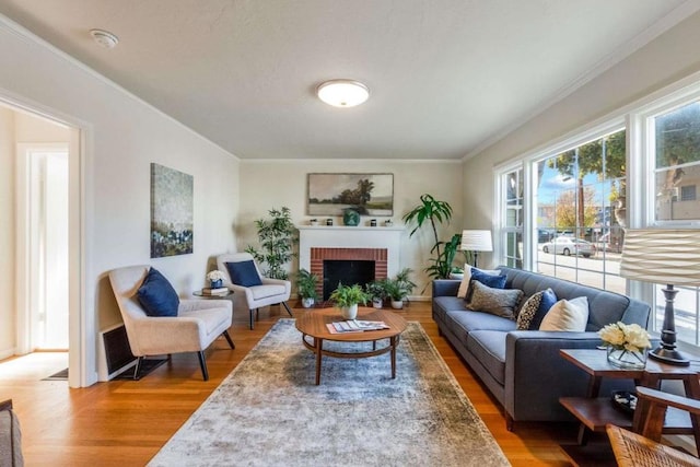 living room featuring hardwood / wood-style flooring, crown molding, a wealth of natural light, and a brick fireplace