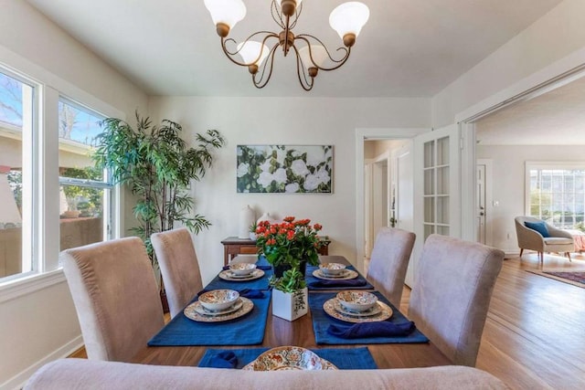 dining room with wood-type flooring, plenty of natural light, and a notable chandelier