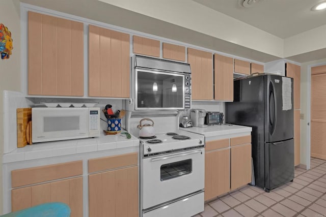 kitchen featuring light brown cabinets, light tile patterned flooring, and white appliances