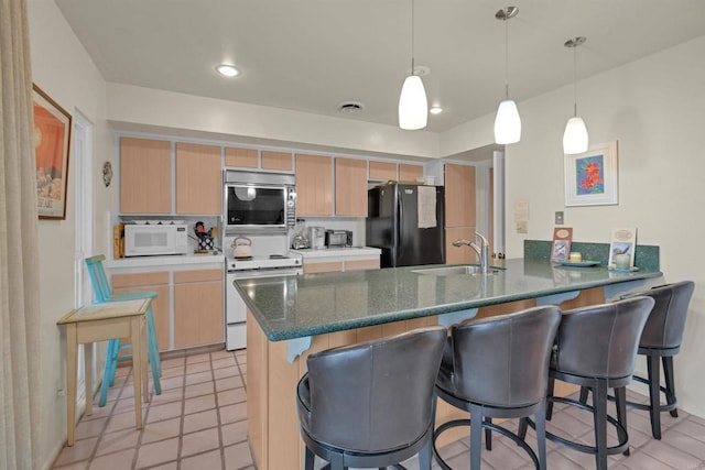 kitchen with white appliances, sink, light brown cabinetry, decorative light fixtures, and kitchen peninsula