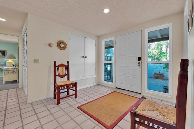 entryway with light tile patterned floors and a textured ceiling