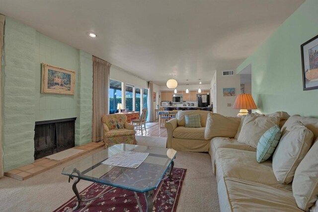 living room featuring light carpet and a fireplace