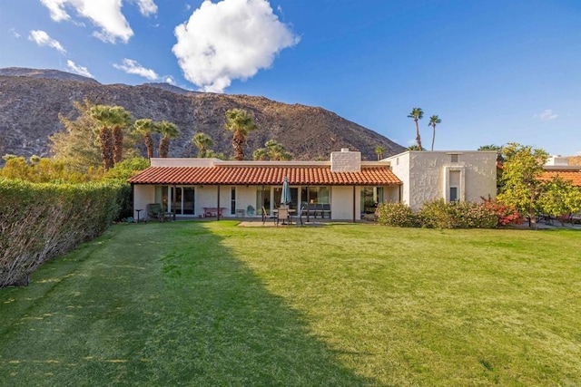 rear view of property with a mountain view and a yard