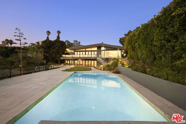 pool at dusk with a patio area