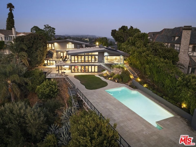 pool at dusk featuring a patio