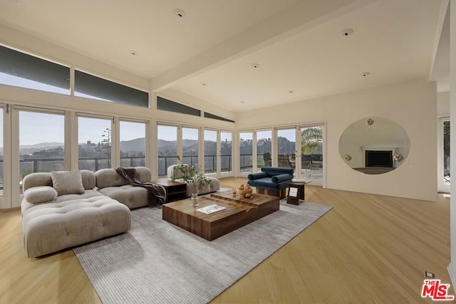 living room featuring vaulted ceiling with beams, a mountain view, and light hardwood / wood-style flooring