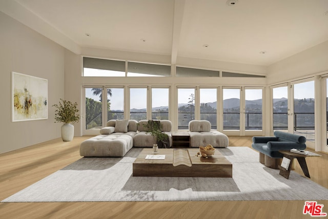 sunroom with vaulted ceiling with beams, a mountain view, and a healthy amount of sunlight