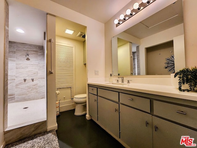 bathroom with vanity, toilet, and a tile shower