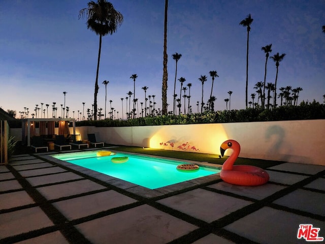 pool at dusk with a patio area