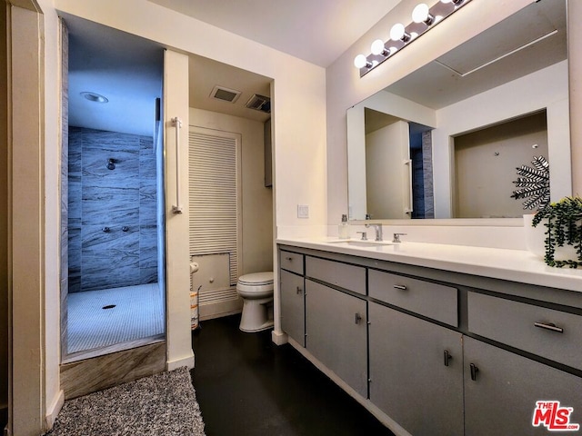 bathroom featuring tiled shower, vanity, and toilet