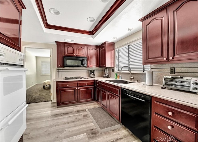 kitchen featuring decorative backsplash, black appliances, sink, a raised ceiling, and light hardwood / wood-style flooring