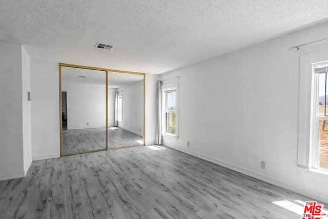 unfurnished room featuring light hardwood / wood-style floors and a textured ceiling