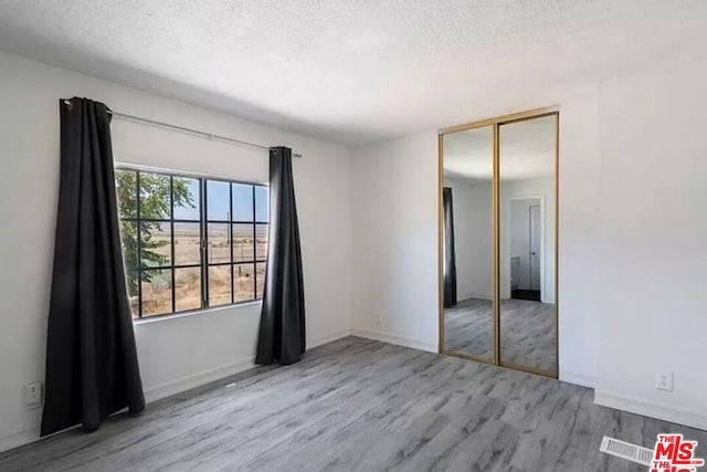 empty room featuring light hardwood / wood-style floors and a textured ceiling